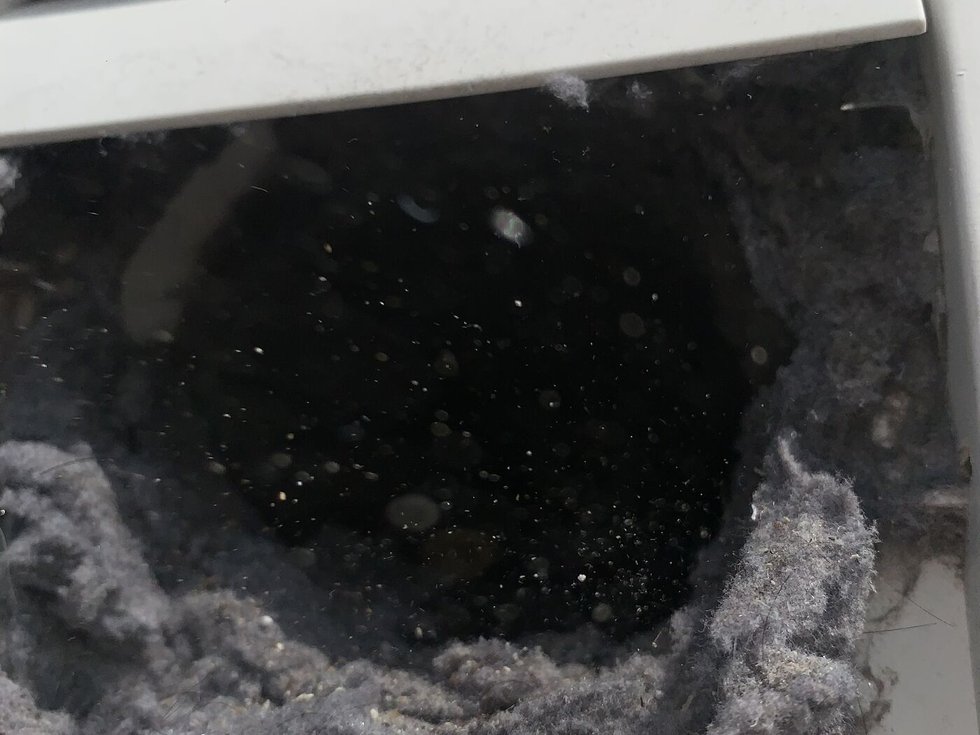 Close-up of compacted lint blocking the dryer vent duct opening